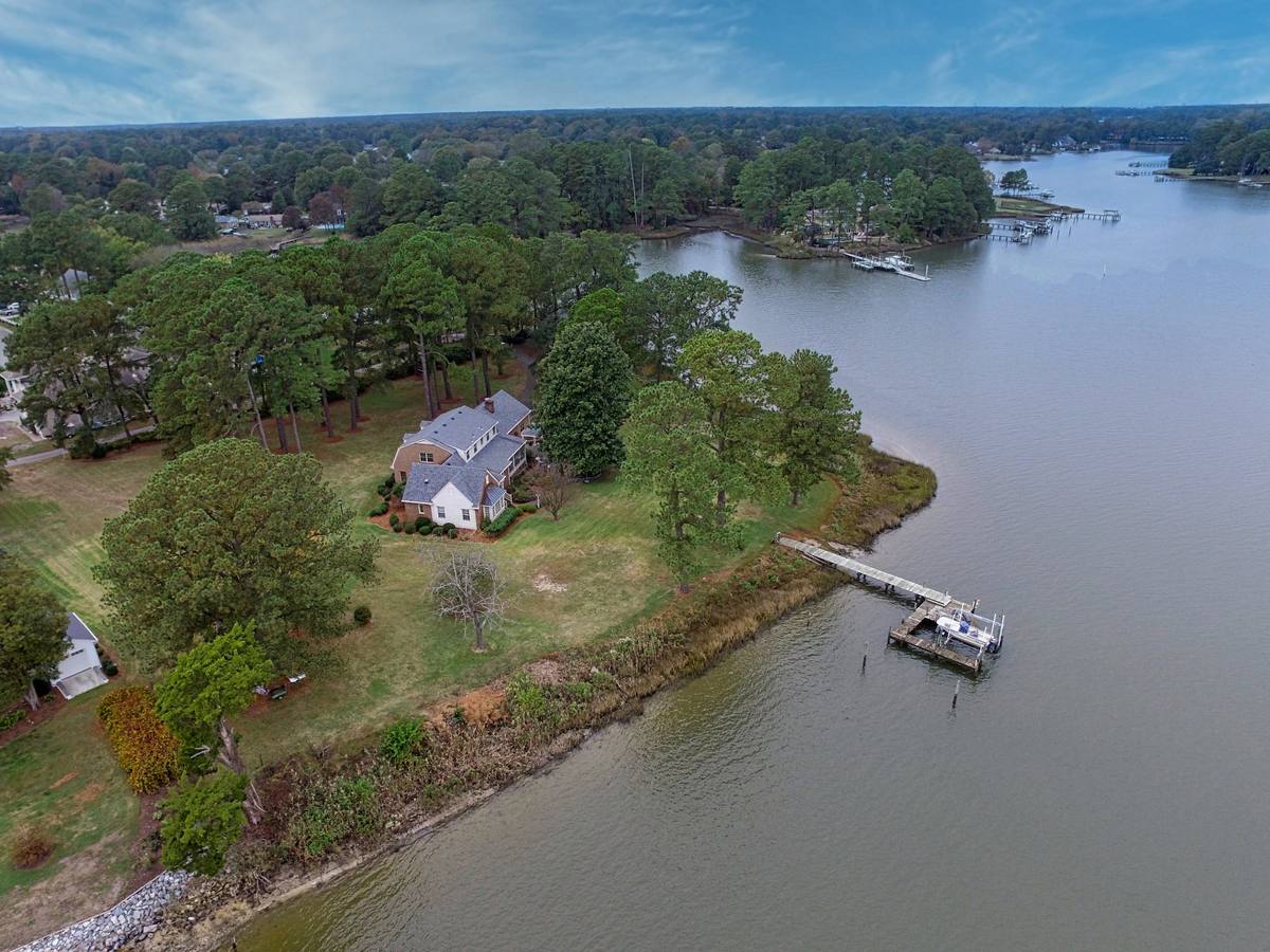 Aerial view of a waterfront home in Chesapeake with a private pier and boat lift on a tidal creek lined with docks